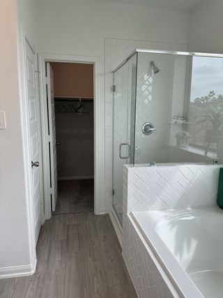 A modern bathroom with wood floors, a glass shower, and stylish white tile accents.