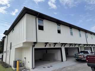 Modern white townhouse with open garages in Koenig Townhomes by Milestone Community Builders (Austin, TX).