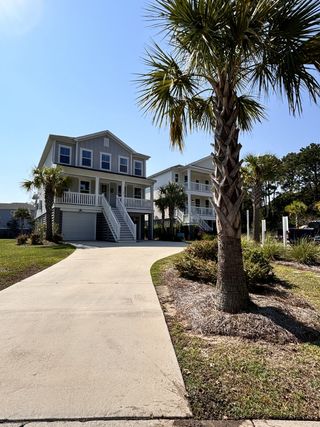 A charming gray home with palm trees and a spacious driveway in Liberty Hill Farm by K. Hovnanian® Homes (Mount Pleasant, SC).