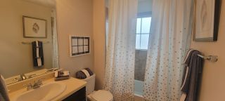 Model Home A cozy bathroom with a vanity, framed artwork, and a shower curtain, offering a simple and functional design.