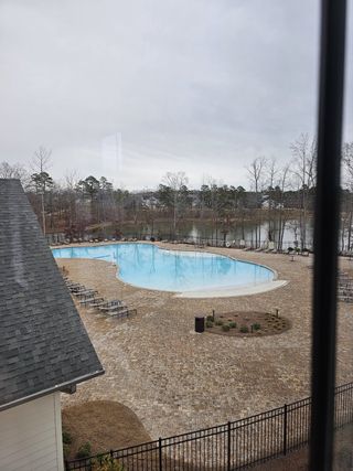 A scenic outdoor pool with a beautiful lake view, resort-style seating, and a tranquil atmosphere at Cresswind Georgia at Twin Lakes by Kolter Homes in Hoschton, GA.