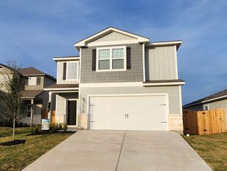 Charming grey two-story home with a spacious driveway in Homestead Estates by LGI Homes, Elgin, TX.