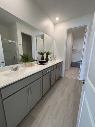 A modern bathroom featuring a long vanity with dual sinks, sleek mirrors, and elegant neutral tile flooring.