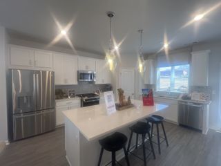 A modern kitchen with sleek white cabinetry, stainless steel appliances, and a spacious island with pendant lighting.