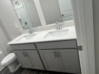 Model Home A modern bathroom featuring a dual sink vanity, sleek chrome faucets, and soft gray cabinetry.