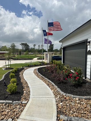 A charming home with a landscaped walkway and flags in Maple Heights by Century Communities (Porter Heights, TX).