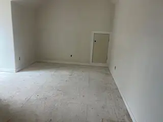 A minimal room with white walls, vaulted ceiling, and an attic access door, ready for finishing touches.