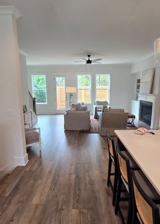 Model Home An inviting living area with wooden floors, modern seating, and a cozy fireplace framed by large windows.