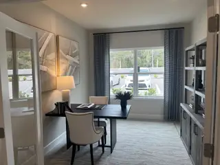 Model Home A modern home office with a sleek desk, elegant artwork, and ample natural light through large windows.