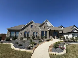 Street view A charming stone home with meticulous landscaping in Homestead by Coventry Homes (Schertz, TX).