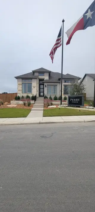 A beautifully designed Perry Homes model in Ladera, San Antonio, TX. Featuring modern stone and brick exteriors with a landscaped front yard.