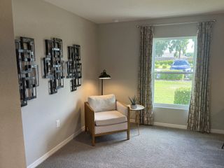 Model Home A cozy nook featuring a modern accent chair, sleek side table, geometric wall art, and a large window with patterned curtains.