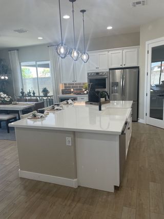 Model Home Modern kitchen with a spacious island, pendant lighting, and stainless steel appliances.
