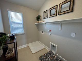 Model Home A cozy laundry room with bright window, utility racks, decorative frames, and functional pet space.