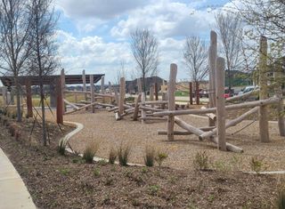 A natural playground with wooden structures in The Grove Frisco by Chesmar Homes (Frisco, TX).