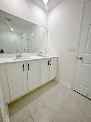 Elegant bathroom with dual sinks, large mirror, and sleek white cabinetry for a clean, modern look.