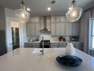Model Home A modern kitchen with sleek gray cabinets, a spacious island, and stylish pendant lights.