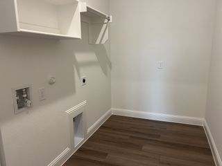 Model Home A modern laundry room with wood flooring, open shelving, and utility connections for convenience.