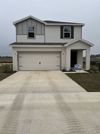 Street view A modern two-story home with a double garage in Bennah Oaks by Highland Homes of Florida (Belleview, FL).