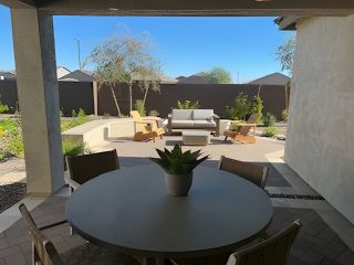 A cozy patio with a round table, plush seating, and lush greenery, perfect for outdoor relaxation and entertaining.