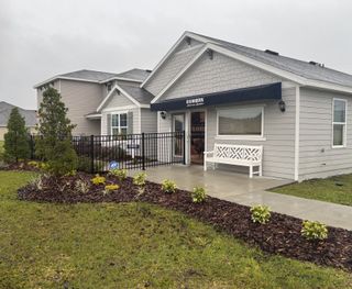 Street view A charming gray home with lush landscaping in Avalon Woods by D.R. Horton (Newberry, FL).