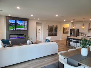 A modern living area with sleek fireplace, wall-mounted TV, and open-plan kitchen, perfect for relaxation and entertainment.