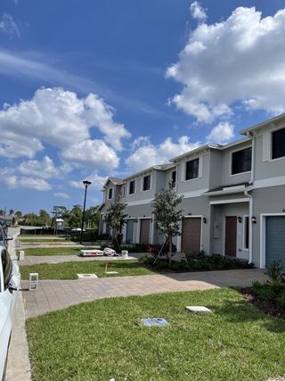 A charming row of townhomes with manicured lawns in Ashwood Cove by D.R. Horton (Lake Worth, FL).