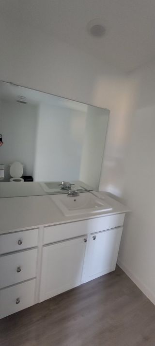 A modern bathroom with a sleek white vanity, spacious mirror, and elegant fixtures.