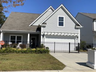 Street view A charming white home with a manicured lawn and inviting porch in Village at Northtown by KB Home (Pflugerville, TX).