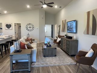 A cozy living room featuring elegant furnishings, wooden flooring, and abstract art, perfect for relaxation and entertainment.