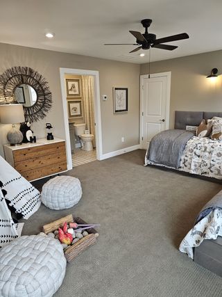 A cozy bedroom with a neutral palette, modern ceiling fan, and an ensuite bathroom, designed for comfort and relaxation.
