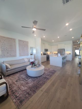 Model Home A spacious living area with a sleek ceiling fan, modern furniture, and an inviting open kitchen layout.