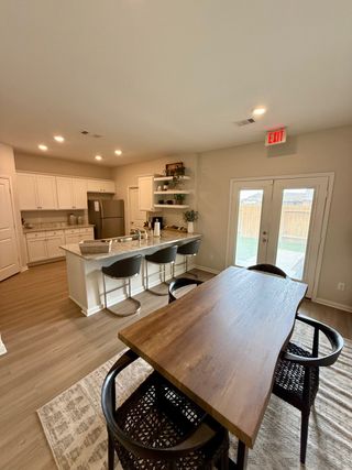 Model Home A modern kitchen with granite island, sleek stools, and wooden dining table, providing a spacious and inviting atmosphere.