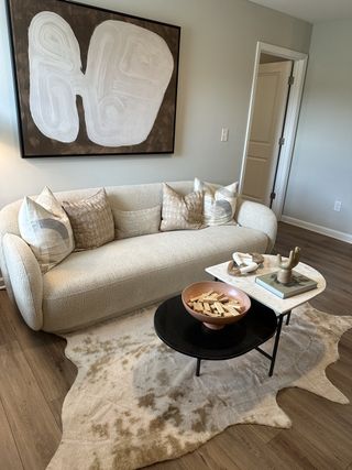 Model Home A chic living room with a textured sofa, abstract art, and stylish coffee table on a soft patterned rug.