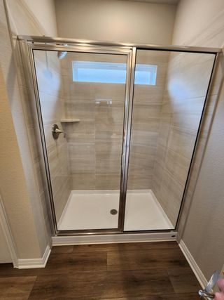A modern glass-enclosed shower with elegant beige tiling and a built-in ledge for convenience.