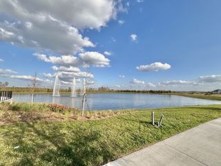 Community Amenities Scenic lakeside view with fountains under a blue sky in EverBe: Venture Townhomes by Lennar (Orlando, FL).
