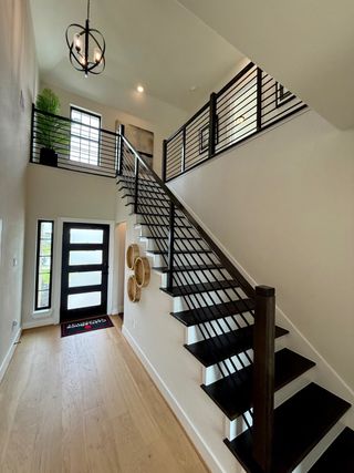 A modern entryway with sleek black railings, wood flooring, and stylish lighting, creating a welcoming atmosphere.