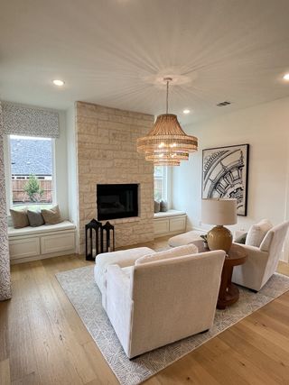 A cozy living room featuring a stone fireplace, plush seating, and a woven chandelier for elegant ambiance.