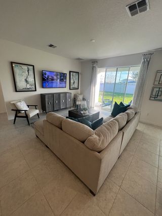  A stylish living space with a cozy sectional, sleek décor, and natural light pouring in from a large sliding glass door.