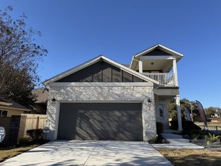 Street view A charming stone-accented home with a spacious balcony in Blanco Vista by Pacesetter Homes (San Marcos, TX).