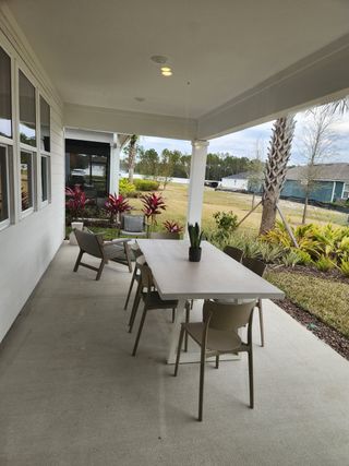 A peaceful covered patio with a dining area overlooking the backyard, offering a perfect space for outdoor gatherings and relaxation.