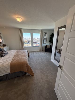 A cozy bedroom with plush carpeting, a large window, and elegant decor in neutral tones.