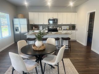 Model Home A charming eat-in kitchen features white cabinetry, a stylish backsplash, and a round dining table set perfect for casual meals.