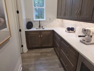 A sleek kitchen nook with modern appliances, dark wood cabinetry, and bright countertop.