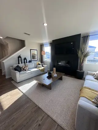 A cozy living room featuring a sleek fireplace, plush sofas, and a large rug on wooden floors, exuding modern elegance.