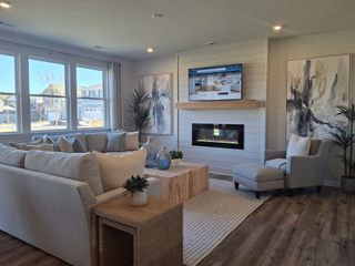 A cozy living room featuring a sectional sofa, fireplace, modern artwork, and ample natural light with stylish decor.