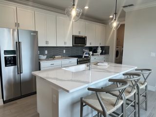 Model Home A sleek modern kitchen with white shaker cabinets, quartz countertops, and a spacious island with seating.