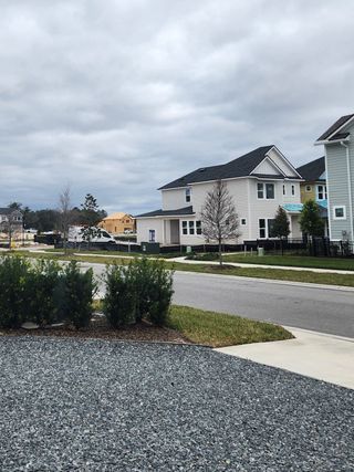 A cloudy street view in Granville at eTown by David Weekley Homes (Jacksonville, FL) shows modern two-story homes with siding under a cloudy sky.