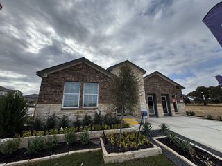 A charming stone and brick home with lush landscaping in Woodfield Preserve: Highlands Collection by Lennar (Georgetown, TX).