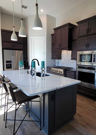Model Home A modern kitchen with dark cabinetry, stylish pendant lights, and a spacious island with marble countertops.